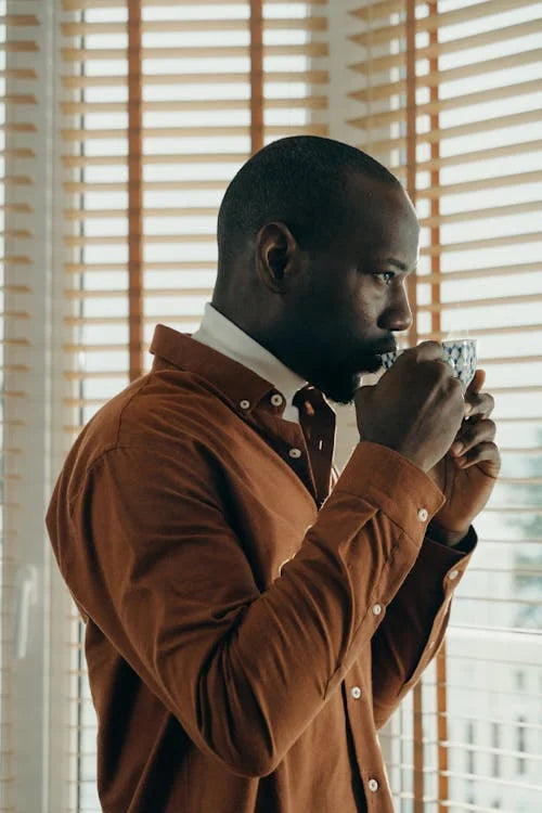 a man standing in front of a window holding a cup