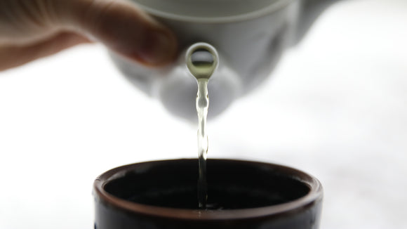 a person pouring water into a cup with a spoon