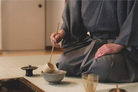 a person sitting on a mat with a bowl and spoon