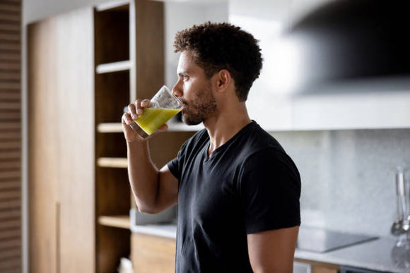 a man drinking from a glass in a kitchen